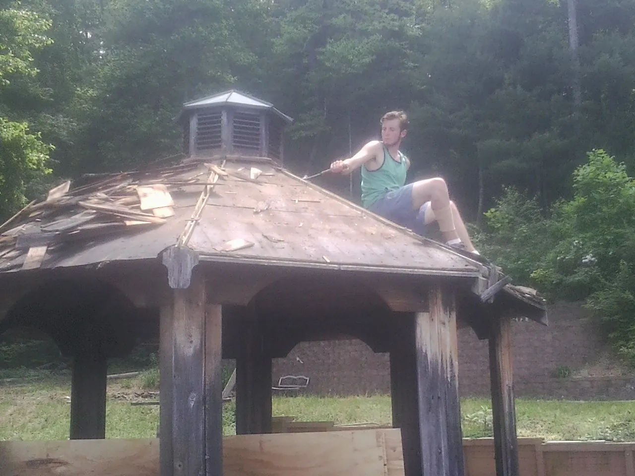 Tearing the old roof off a wooden gazebo before new shakes in Long Pond