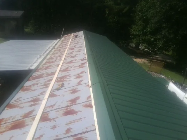 Old rusted panels beside newly installed green metal roofing — Wind Damage Roof Repair by Roofing Brothers in Long Pond