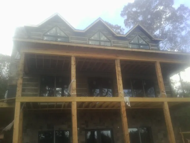 Dormers and porch framing on a large log home under construction — Roof Coating work by our crew in Long Pond