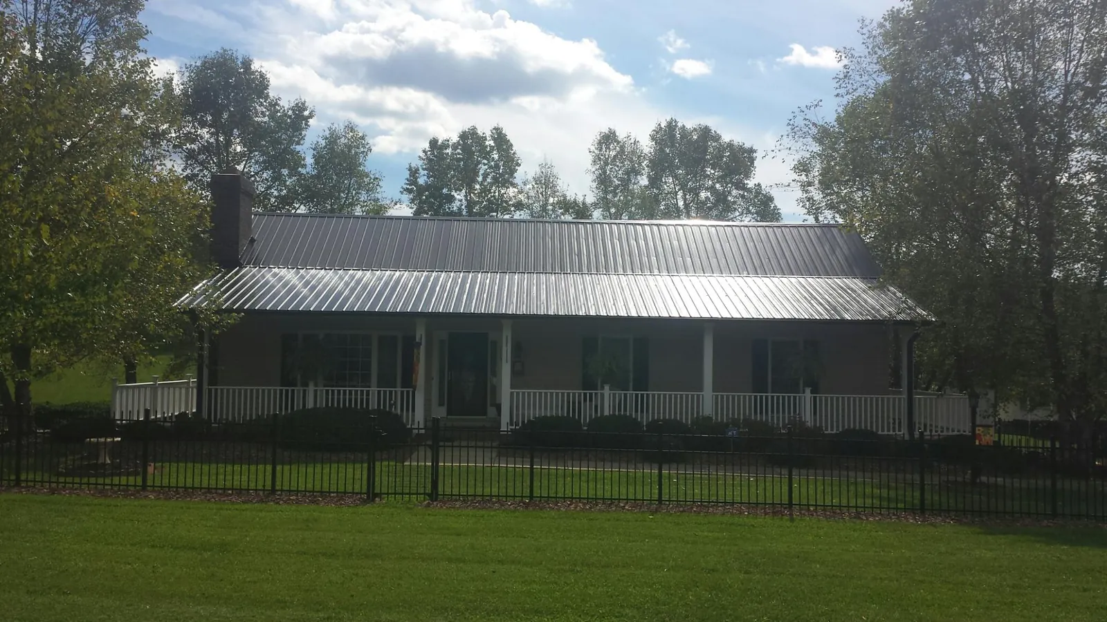 Gray metal roof on a brick ranch with a full width front porch — Gutter Guard Installation work by our crew in Long Pond