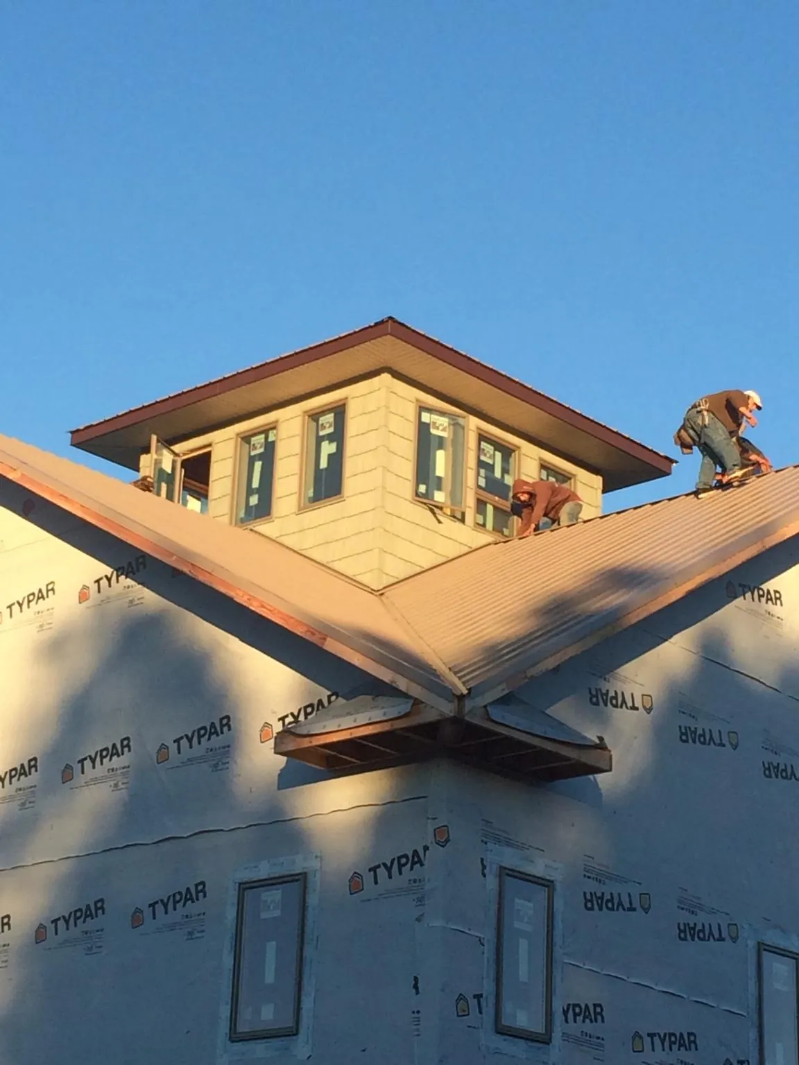 Roofers working around a rooftop cupola on a new metal roof at sunset — Roof Waterproofing in Long Pond by Roofing Brothers